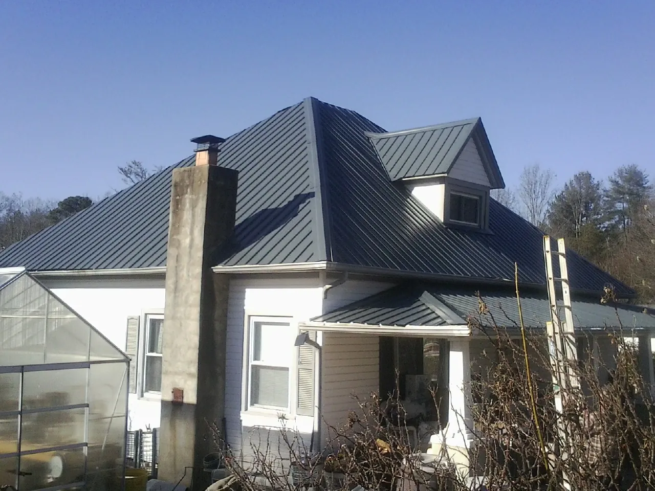 Dark blue standing seam metal roof on a white farmhouse with dormer — Slate & Tile Roof Repair by Roofing Brothers in Eau Claire