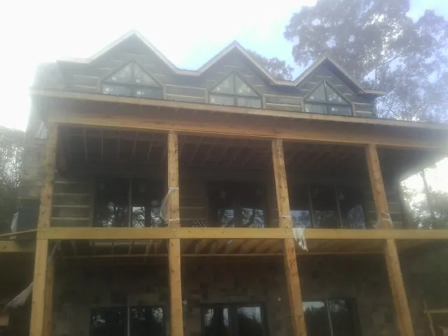 Dormers and porch framing on a large log home under construction — Roof Coating work by our crew in Eau Claire