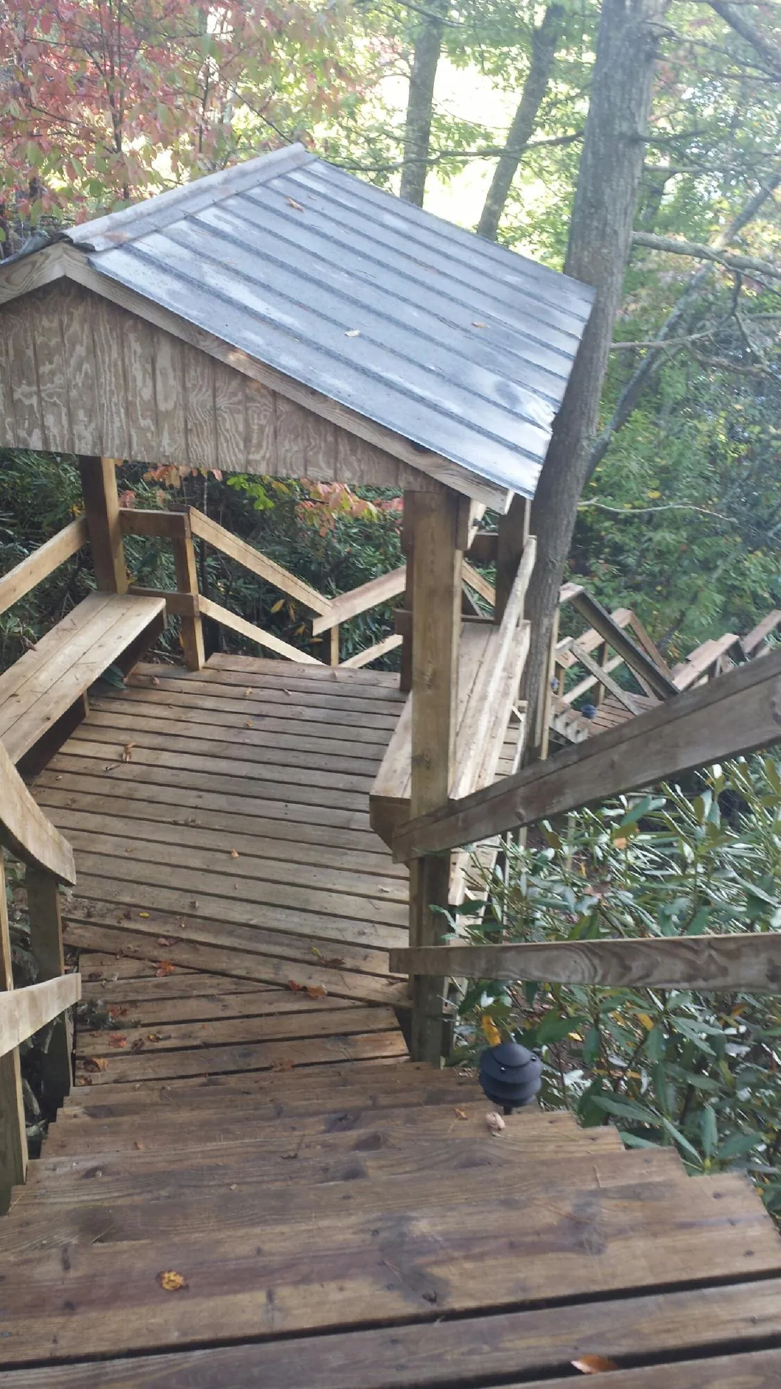 Metal roofed shelter over wooden steps on a wooded walkway — Skylight Repair & Installation work by our crew in Eau Claire