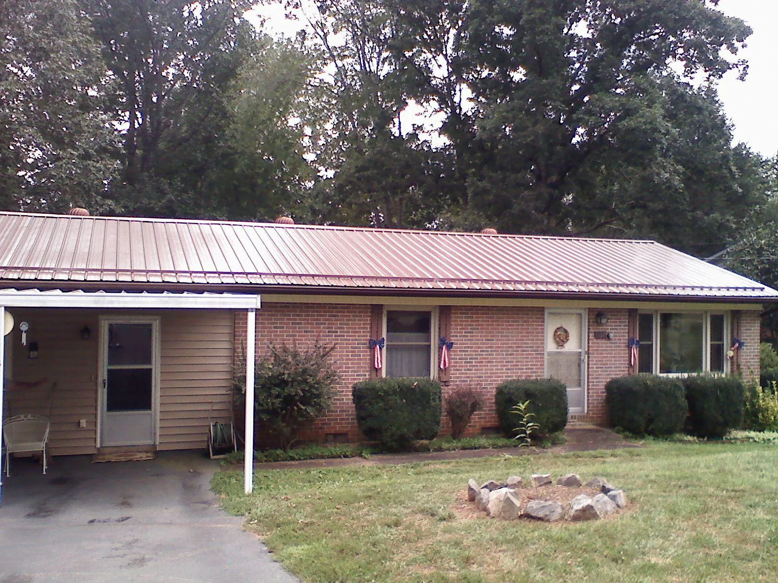 Bronze metal roof and carport on a brick ranch home — Roof Repair work by our crew in Eau Claire